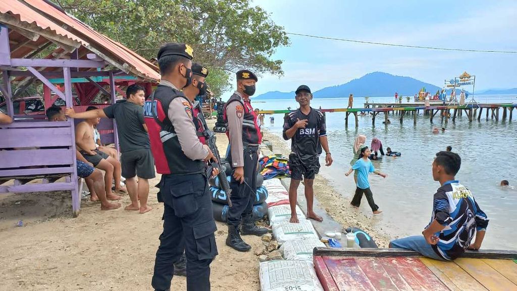 Anggota polisi dari Polres Pesawaran mengimbau wisatawan agar berhati-hati saat bermain di Pantai Mutun di Kabupaten Pesawaran, Lampung, pada Senin (26/12/2022). 