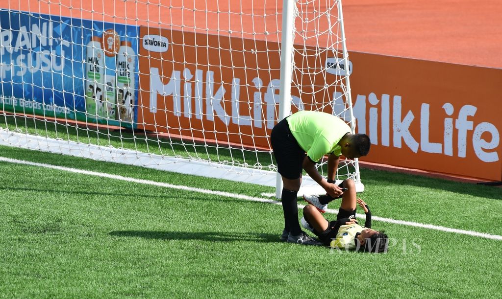 Wasit memeriksa kondisi salah satu pemain yang terjatuh dalam pertandingan hari pertama MilkLife Soccer Challenge 2023 Batch 3 yang berlangsung di Stadion Supersoccer Arena, Kudus, Jawa Tengah, Jumat (15/12/2023). 