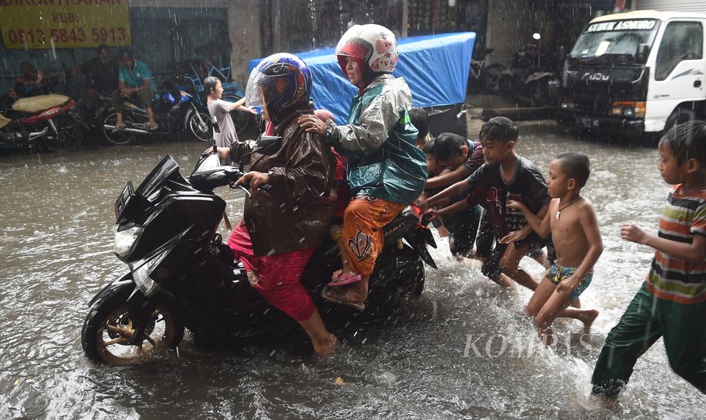 Anak membantu pengendara sepeda motor yang mogok saat banjir di Jalan Jagir Wonokromo Wetan, Surabaya, Jawa Timur, Selasa (11/1/2022). Hujan yang terjadi tidak beberapa lama menyebabkan banjir di jalan tersebut. 