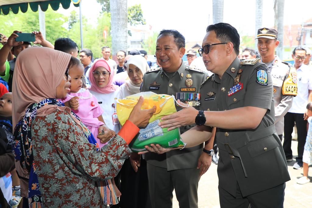 Penjabat Gubernur Jatim Adhy Karyono menyerahkan beras SPHP bulog kepada masyarakat yang berbelanja di pasar murah di kantor Kelurahan Tegal Besar, Jember, Rabu (6/3/2024). 