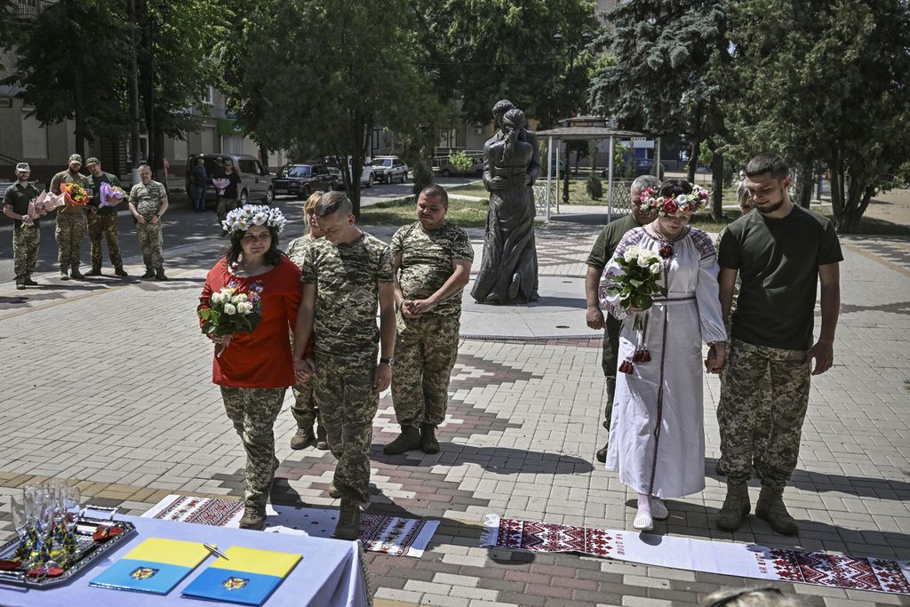 Tentara Ukraina, Kristina (kedua dari kanan) dan Vitaliy Orlich serta Khrystyna Lyuta (kiri) dan Volodymyr Mykhalchuk, menikah di kota Druzhkivka, wilayah Donbas, Ukraina timur, 12 Juni 2022. 