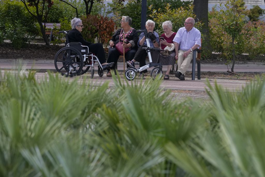 Warga lansia duduk bersama di taman pada suatu sore yang hangat di Madrid, Spanyol, 13 Mei 2024. 