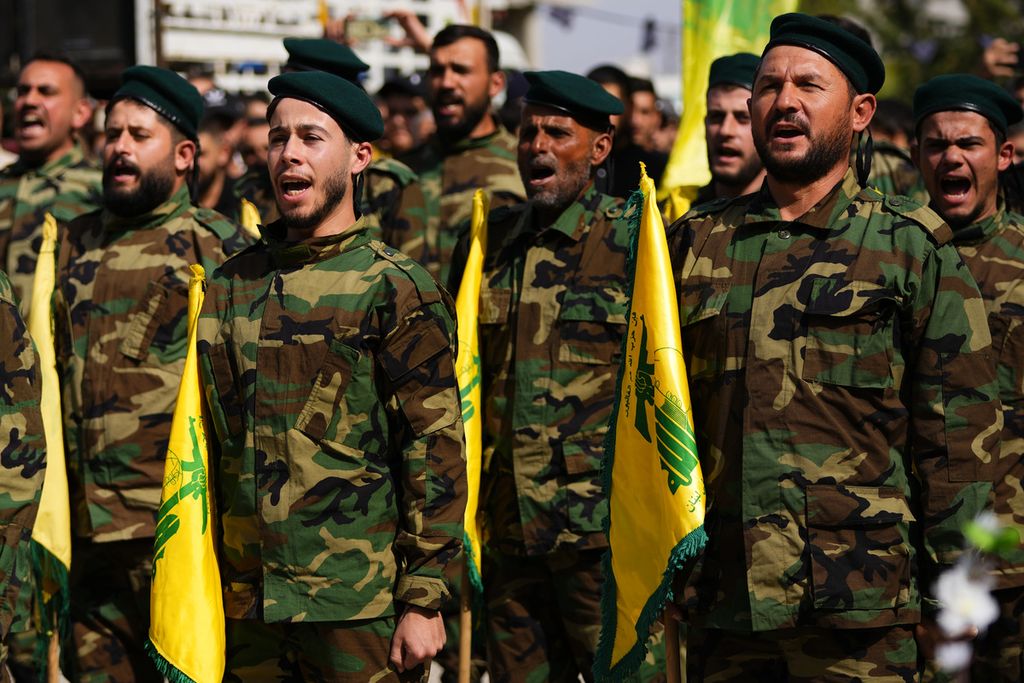 Anggota pasukan Hezbollah meneriakkan yel-yel penyemangat saat mereka menghadiri upacara pemakaman seorang petempur anggota  Hezbollah, yang tewas akibat gempuran artileri Israel, di Desa Majadel, Lebanon selatan, Minggu (22/10/2023). 