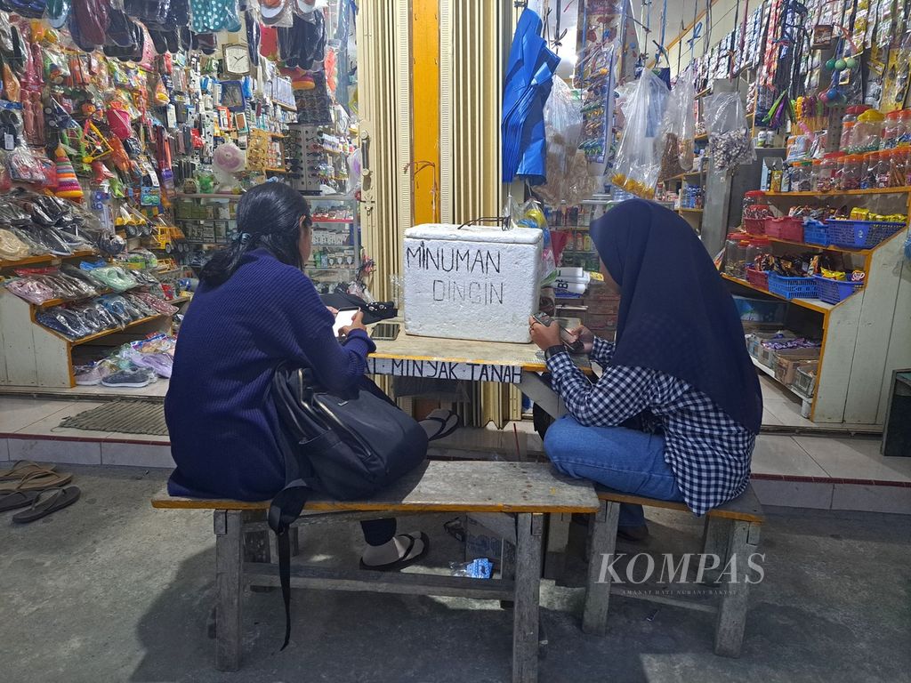 Dua perempuan mengakses Wi-Fi berbayar dari internet satelit untuk urusan pekerjaan di sebuah warung di dermaga Polaga, Desa Sikakap, Kecamatan Sikakap, Kepulauan Mentawai, Sumatera Barat, Rabu (21/6/2023) jelang malam. 