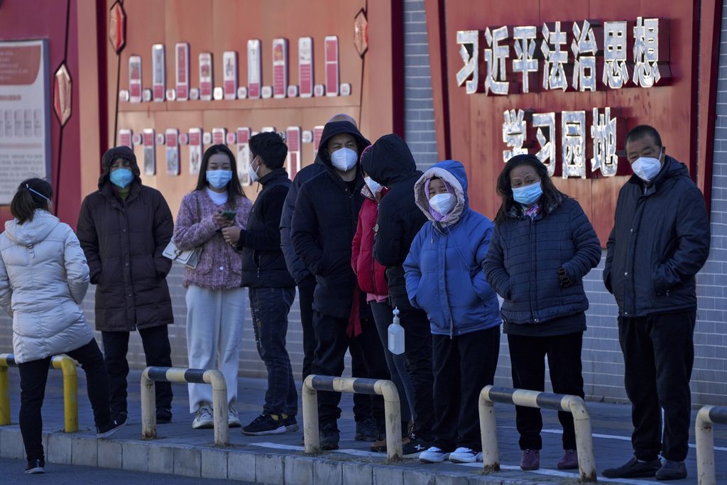 Warga dengan menggunakan masker wajah berbaring mengantre untuk melakukan tes usap rutin di Beijing, Senin (5/12/2022). 