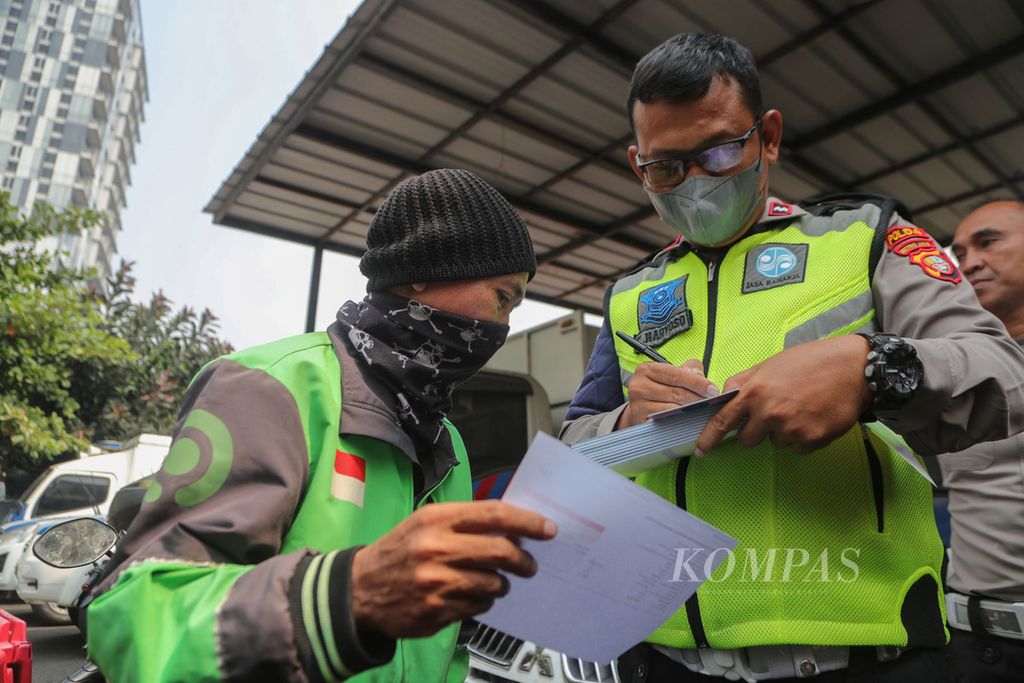Anggota polisi menulis surat tilang kepada pengemudi daring yang tidak lolos uji emisi di Kantor Subdit Gakkum Ditlantas Polda Metro Jaya, Jakarta Selatan, Jumat (1/9/2023). 