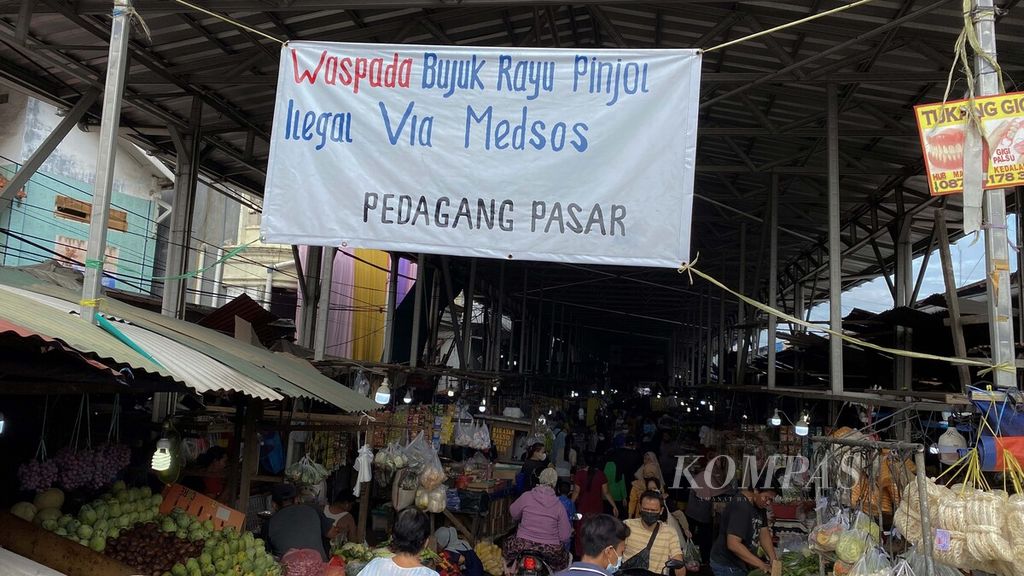 Spanduk ajakan untuk mewaspadai praktik pinjaman daring (pindar) ilegal menghiasi pintu masuk Pasar Muara Angke, Penjaringan, Jakarta Utara, Minggu (14/11/2021). Saat ini setidaknya telah ada lebih dari 19.700 pengaduan pindar ilegal ke Otoritas Jasa Keuangan (OJK). Bukan hanya soal bunga tinggi yang tidak disadari oleh nasabah, praktik penagihan utang di pindar juga seringkali menerapkan intimidasi.