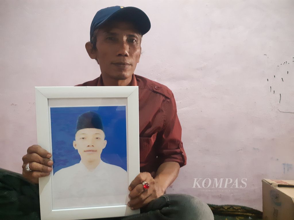 Rusdi (47) memegang foto anak sulungnya, Albar Mahdi (17), yang meninggal dunia diduga akibat dianiaya oleh seniornya di Pondok Modern Darussalam Gontor, Ponorogo, Jawa Timur, Jumat (9/9/2022). Rusdi meminta keadilan agar pelaku ditindak sesuai dengan hukum yang berlaku.