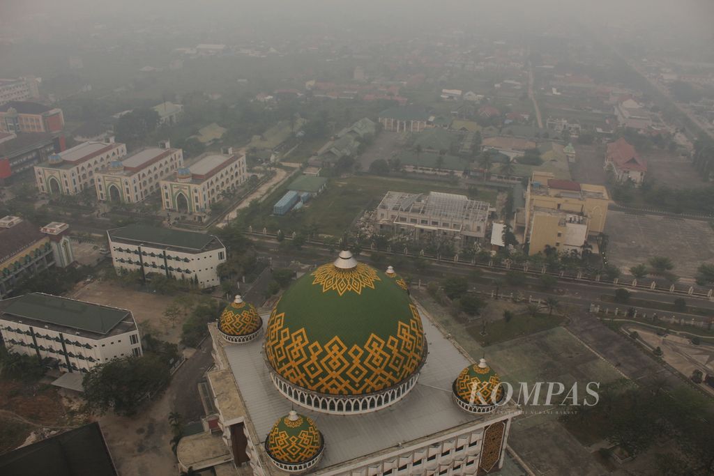 Masjid Raya Darussalam, Palangkaraya, Kalimantan Tengah, mulai tertutup kabut asap akibat kebakaran hutan dan lahan yang kian masif pada Rabu (4/10/2023). Kualitas udara di Palangkaraya masuk kategori tidak sehat.
