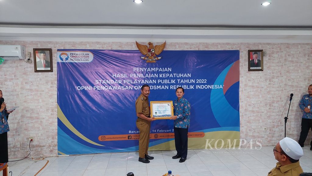 Kepala Perwakilan Ombudsman Kalimantan Selatan Hadi Rahman (kanan) memberikan piagam penghargaan kepada Wakil Wali Kota Banjarbaru Wartono (kiri) dalam kegiatan penyampaian hasil penilaian kepatuhan standar pelayanan publik tahun 2022 Opini Pengawasan Ombudsman Republik Indonesia di Banjarmasin, Selasa (14/2/2023).