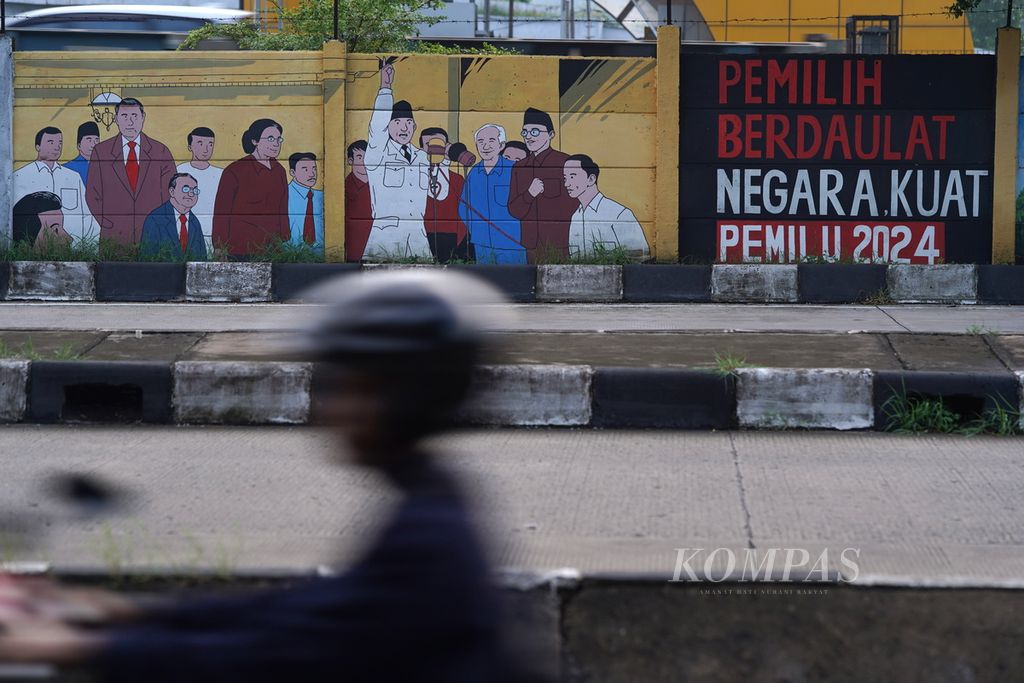 Pengendara sepeda motor melintasi mural pemilih berdaulat di kawasan Pulogebang, Jakarta Timur, Selasa (13/2/2024). 