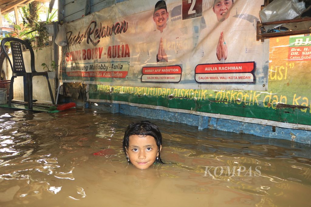Seorang anak beraktivitas di dalam rumahnya yang terendam banjir di Jalan Dipanegara, Padang Bulan, Kota Medan, Sumatera Utara, Sabtu (19/11/2022). Hujan lebat pada Jumat malam membuat sejumlah permukiman dan ruas jalan di Kota Medan tergenang banjir. 