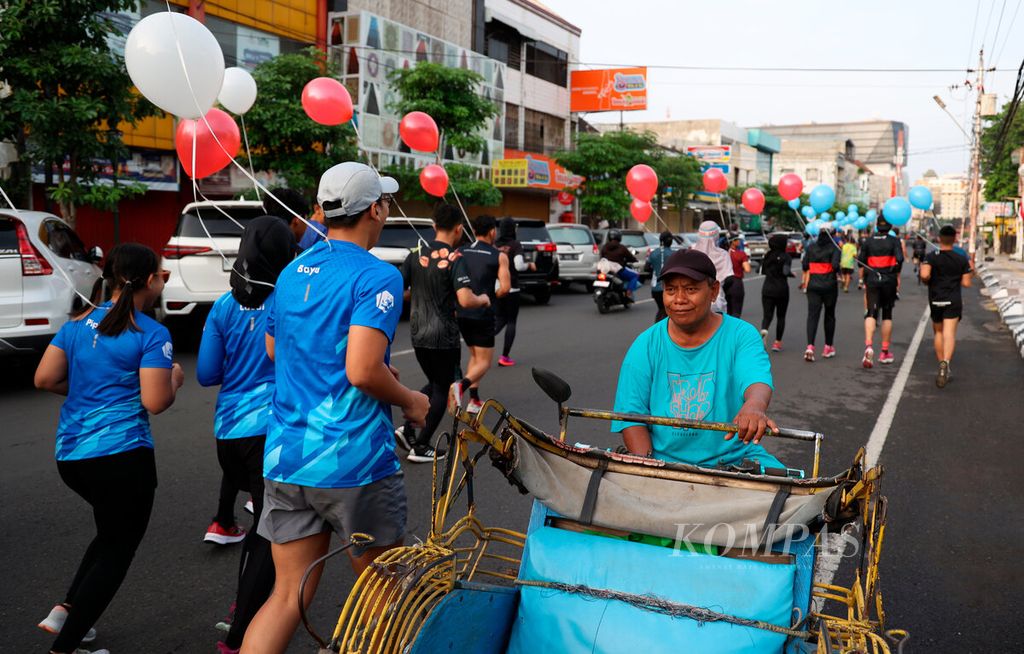 Pengemudi becak berhenti saat berpapasan dengan sejumlah pelari yang berlari bersama dalam rangka memeriahkan peluncuran lomba lari Semarang 10K di Kota Semarang, Jawa Tengah, Minggu (16/10/2022). 