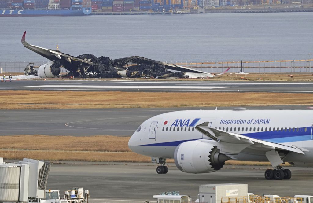 Pesawat Japan Airlines yang terbakar terlihat dari belakang di Bandara Haneda, Rabu (3/1/2024). 