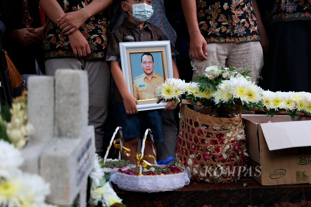 Salah satu keluarga membawa foto Paulus Iwan Boedi Prasetijo, pegawai Badan Pendapatan Daerah Kota Semarang, yang dimakamkan di pemakaman umum Salaman Mloyo, Kota Semarang, Jawa Tengah, Kamis (22/9/2022). 