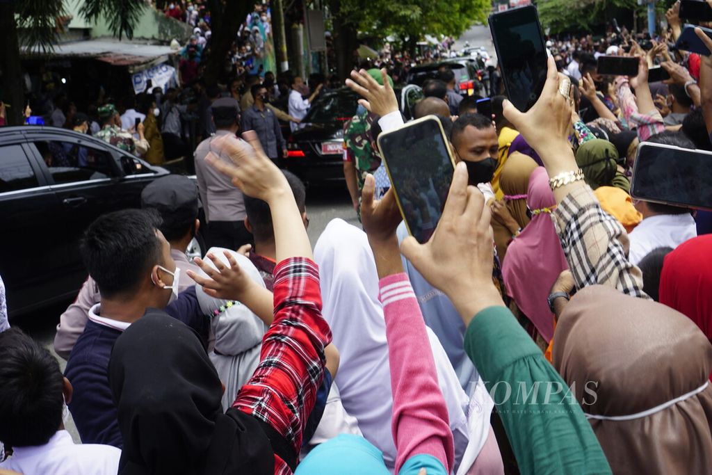 Warga melambaikan tangan kepada Presiden Joko Widodo saat orang nomor satu di Indonesia itu berkunjung ke Pasar Sepinggan, Kota Balikpapan, Kalimantan Timur, Senin (31/1/2022).