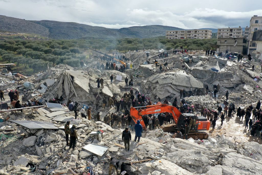 This aerial view shows residents searching for victims and survivors amidst the rubble of collapsed buildings following an earthquake in the village of Besnia near the twon of Harim, in Syria's rebel-held noryhwestern Idlib province on the border with Turkey, on February 6, 2022. - Hundreds have been reportedly killed in north Syria after a 7.8-magnitude earthquake that originated in Turkey and was felt across neighbouring countries. 