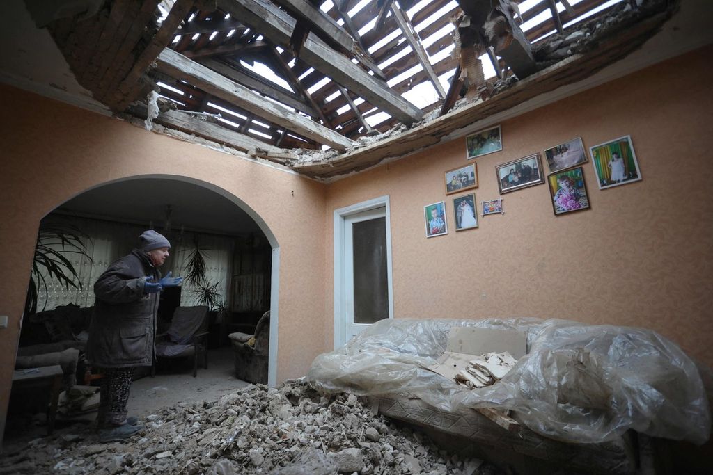 Warga di Desa Stanytsia, Luhanska, wilayah Luhansk, membersihkan puing-puing reruntuhan di rumahnya akibat serangan artileri pasukan separatis dukungan Rusia, Jumat (18/2/2022).