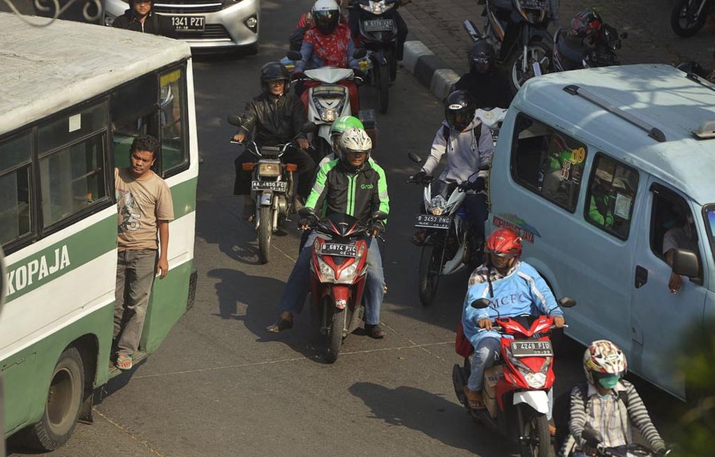 Pengendara ojek daring melintas di dekat angkutan kota di Slipi, Jakarta, Rabu (23/8). Sejumlah pasal dalam Peraturan Menteri Perhubungan Nomor 26 Tahun 2017 Tentang Penyelenggaraan Angkutan Orang dengan Kendaraan Bermotor Umum Tidak Dalam Trayek dicabut oleh Mahkamah Agung. Pasal-pasal Permenhub yang dicabut MA tersebut adalah mengenai tata bertransportasi daring.