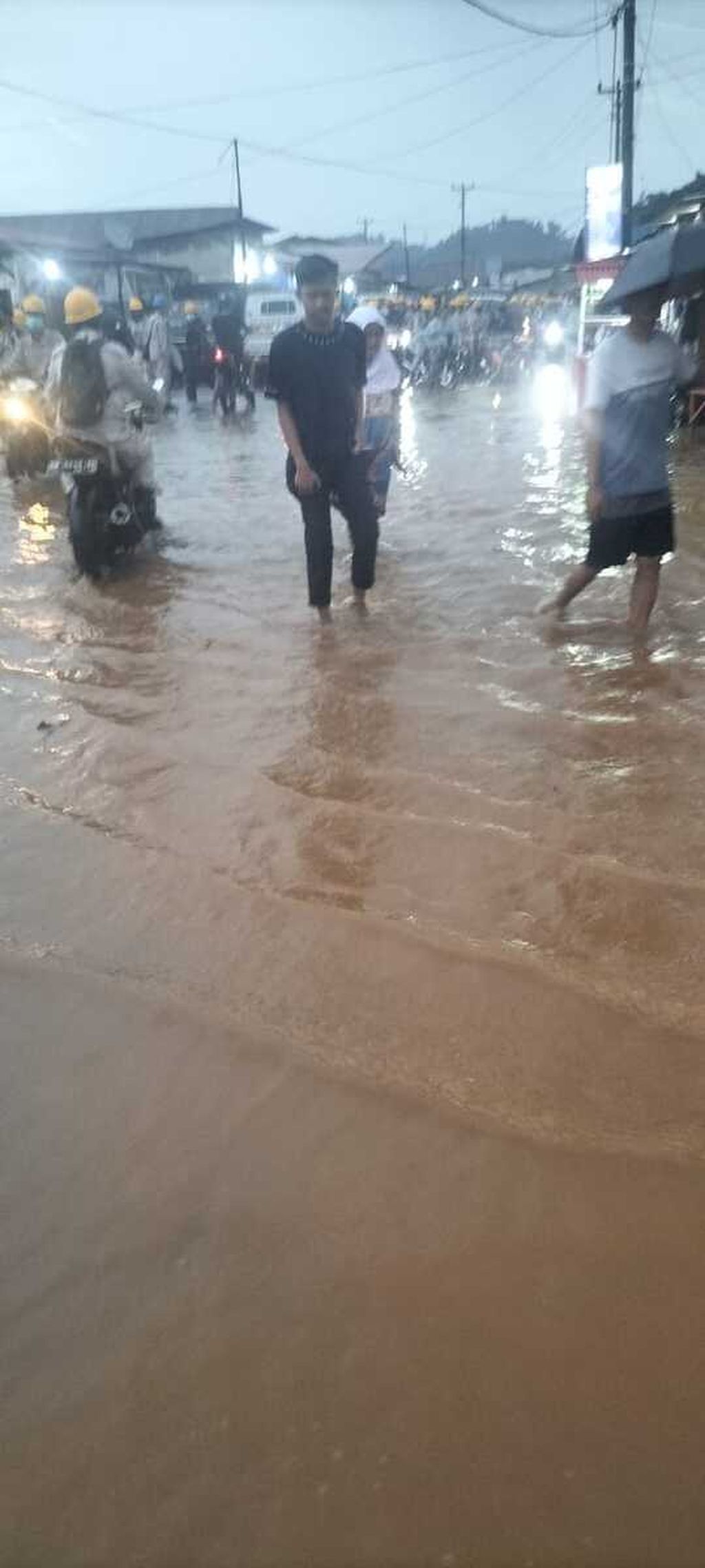 Pengendara dan warga melintasi jalan yang digenangi air di Kecamatan Bahodopi, Kabupaten Morowali, Sulteng, Senin (27/6/2022).