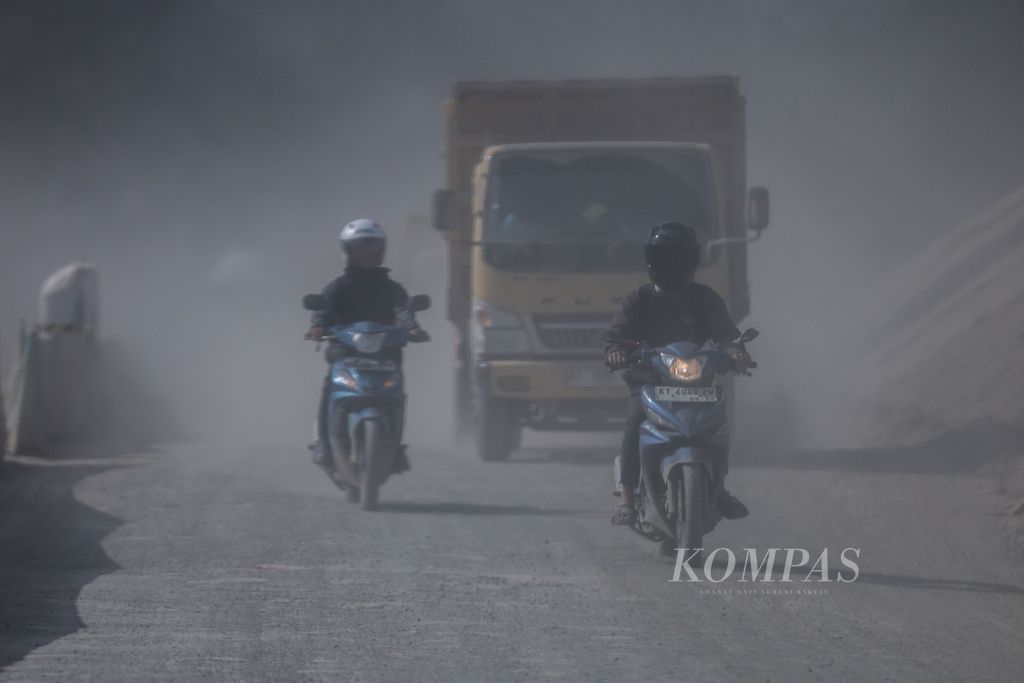 Pengendara sepeda motor melewati kepulan debu di kawasan proyek pembangunan Ibu Kota Nusantara (IKN).