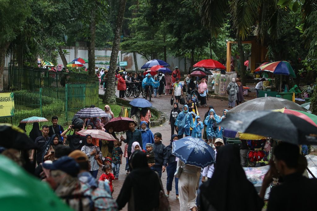 Lalu lalang pengunjung saat hujan di Kebun Binatang Ragunan, Jakarta Selatan, Rabu (28/12/2022). Warga tetap antusias berwisata di tengah potensi hujan ekstrem. 