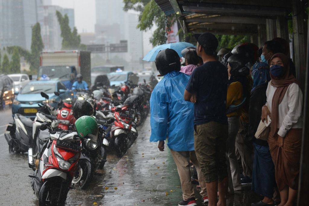 Sejumlah warga berteduh di tempat pemberhentian bus di Jalan Gatot Subroto, Jakarta Selatan, Jumat (9/12/2022). Badan Meteorologi, Klimatologi, dan Geofisika (BMKG) memprediksi wilayah Jakarta Selatan dan Jakarta Timur akan diguyur hujan disertai petir. Diperkirakan puncak musim hujan di sebagian besar wilayah Indonesia akan berlangsung pada Desember 2022 hingga Januari 2023. Khusus di DKI Jakarta, diperkirakan puncak musim hujan akan terjadi pada Januari 2023 sampai Februari 2023. 