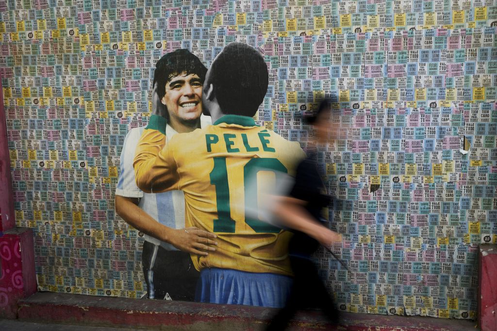 Seorang wanita berjalan di depa mural legenda sepak bola Brasil, Pele, dan legenda sepak bola Argentina, Diego Maradona di Buenos Aires, Argentina, Kamis (29/12/2022). Argentina, Uruguay, Chile, dan Paraguay resmi mengajukan diri sebagai calon tuan rumah Piala Dunia 2030 pada Rabu (8/2/2023).