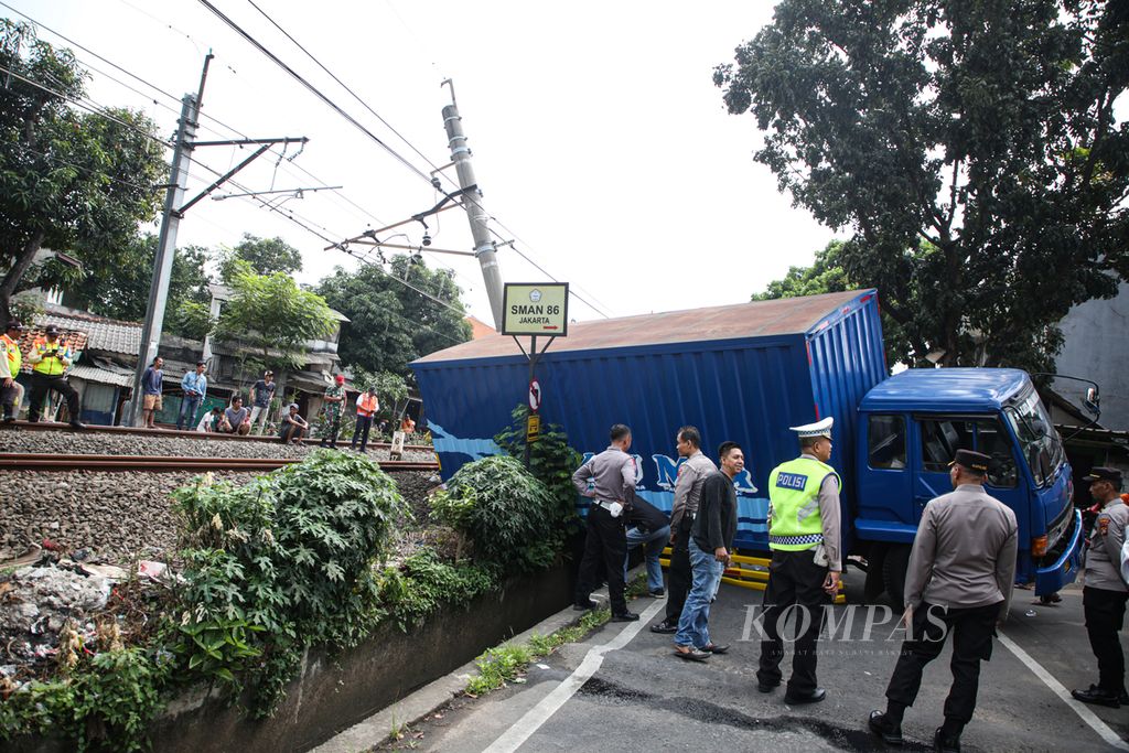 Truk yang terperosok dan menabrak tiang listrik aliran atas kereta komuter di jalan Bintaro Permai, Kecamatan Pesanggrahan, Jakarta Selatan, Selasa (25/7/2023). Peristiwa tersebut menyebabkan terhambatnya perjalanan kereta komuter.