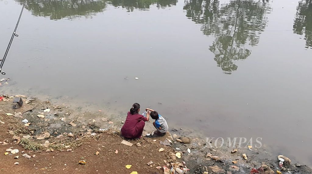 Perempuan dan anak menyiduk air sungai di Drainase Cengkareng, Jakarta Barat, Selasa (15/8/2023).