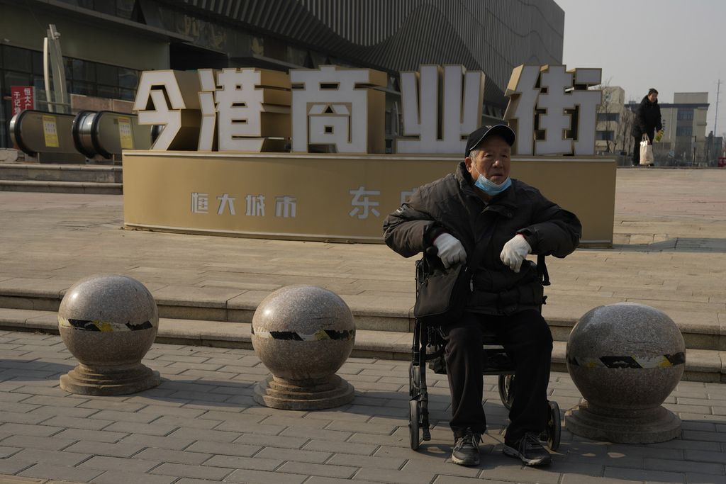 Seorang pria lanjut usia duduk di kursi roda dekat kompleks komersial Evergrande yang sebagian tutup di Beijing, China, 29 Januari 2024. 