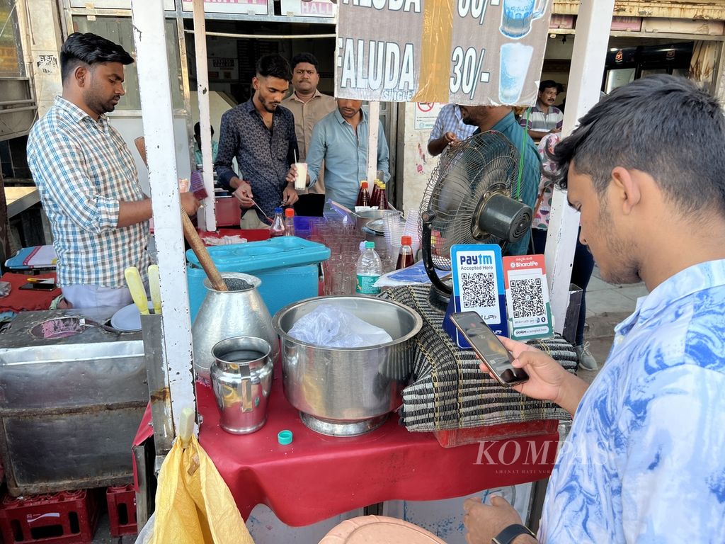 Seorang pembeli membayar minuman menggunakan QRIS di sebuah kios minuman tidak jauh dari tengara kota Hyderabad, Charminar, Rabu(15/2/2023). Pembayaran elektronik di kios-kios pinggir jalan atau pedagang kaki lima adalah pemandangan umum di India.