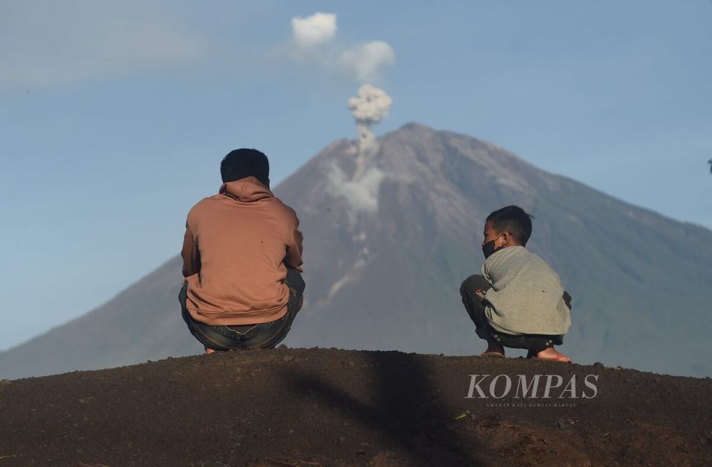 Warga bersama anaknya mengamati Gunung Semeru yang mengeluarkan awan panas guguran di Desa Sumberwuluh, Kecamatan Candipuro, Kabupaten Lumajang, Jatim, Selasa (6/12/2022).