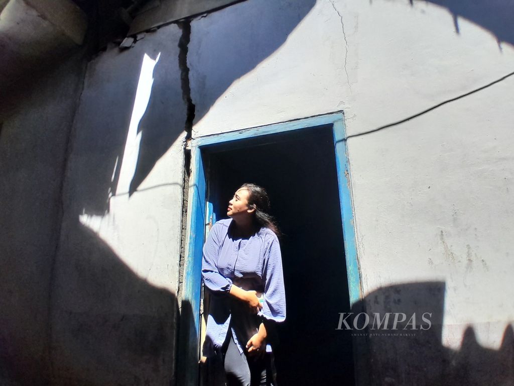 Ifa (32) melongok dinding rumahnya yang retak akibat tanah bergerak di Dusun Brau, Desa Gunungsari, Kecamatan Bumiaji, Kota Batu, Jawa Timur, Minggu (19/3/2024).
