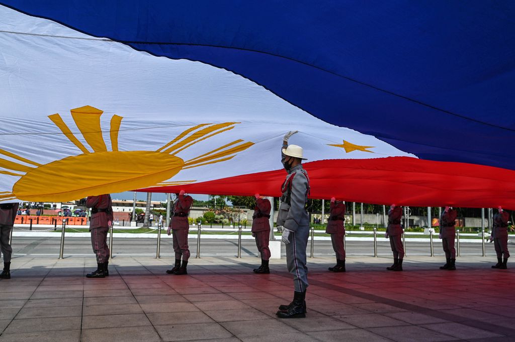 Anggota pasukan kehormatan membawa bendera Filipina raksasa saat upacara hari kemerdekaan ke-124 di Rizal Park, Manila, 12 Juni 2022. 