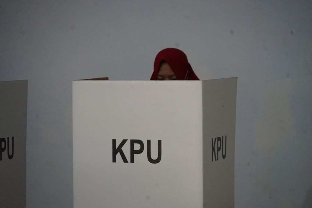 Seorang pemilih datang ke TPS 07 di Maricaya Selatan, Makassar, Sulawesi Selatan, sembari menggendong anak, Rabu (9/12/2020). 