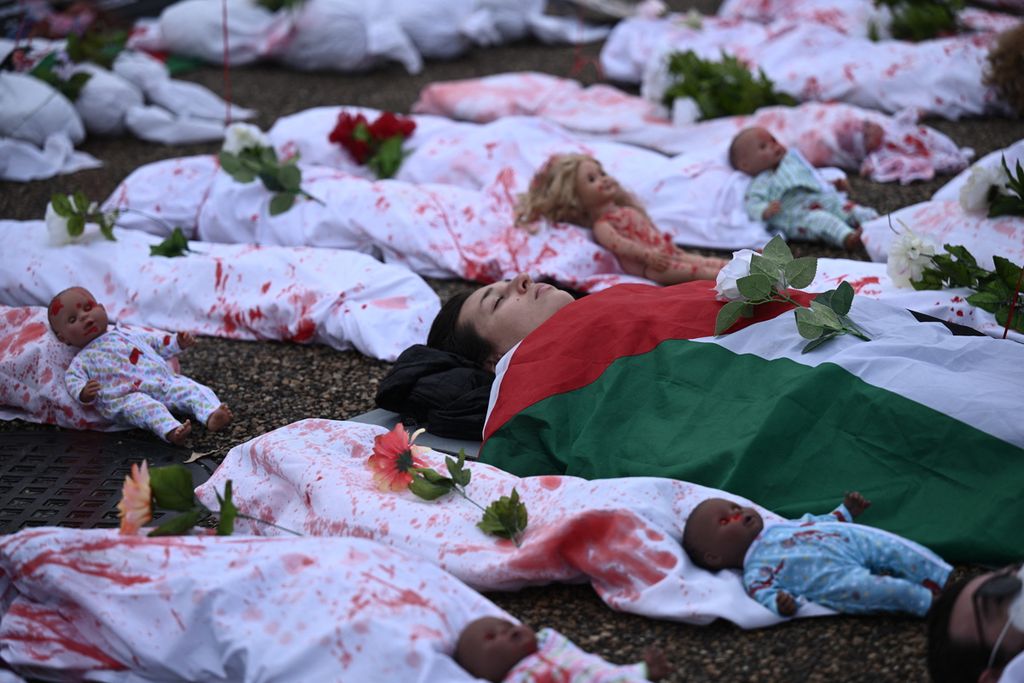 Seorang aktivis berbaring di antara instalasi seni yang melambangkan korban warga sipil Palestina, termasuk anak-anak dan bayi, saat berdemo di depan Gedung Putih, Washington, Amerika Serikat, Sabtu (2/12/2023). 