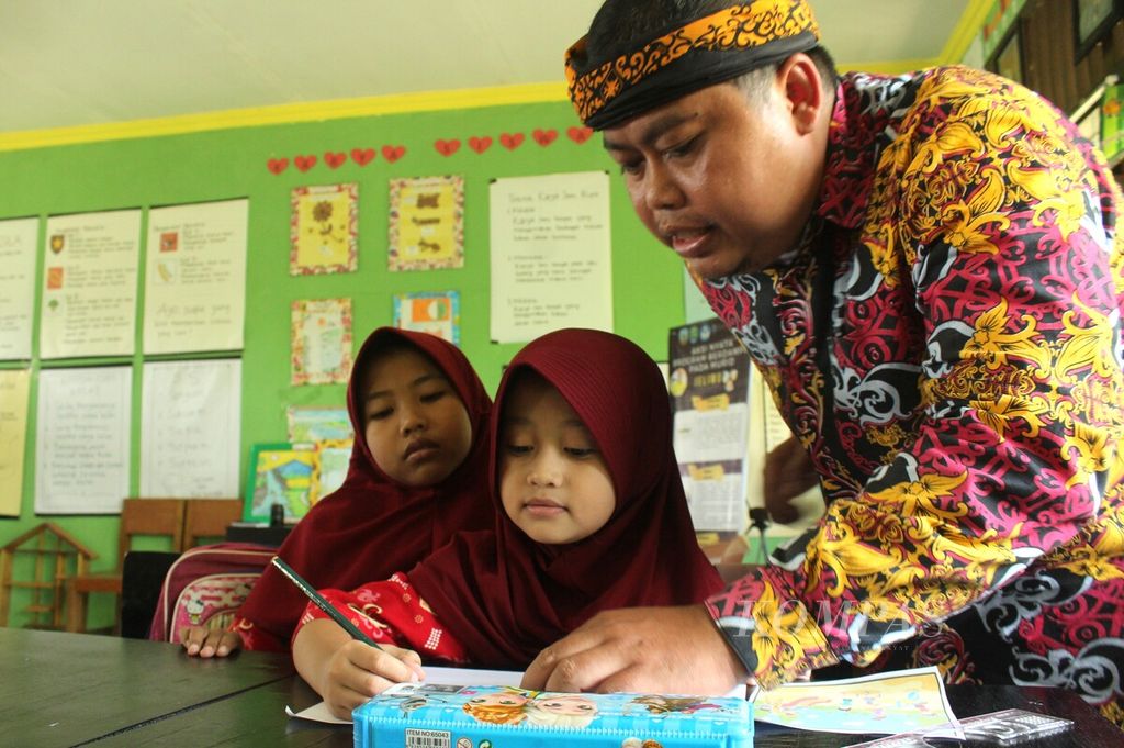 Sudarmuji (35), guru kelas II Sekolah Dasar Negeri 026 Tanjung Selor, Kabupaten Bulungan, Kalimantan Utara, mengajari siswanya menulis cerita, Kamis (13/4/2023).