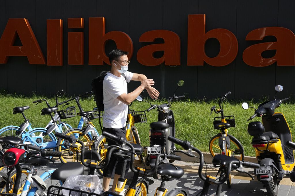 Seorang pria berjalan melintasi logo perusahaan Alibaba di markas besarnya di Beijing, China, 24 Agustus 2021. 