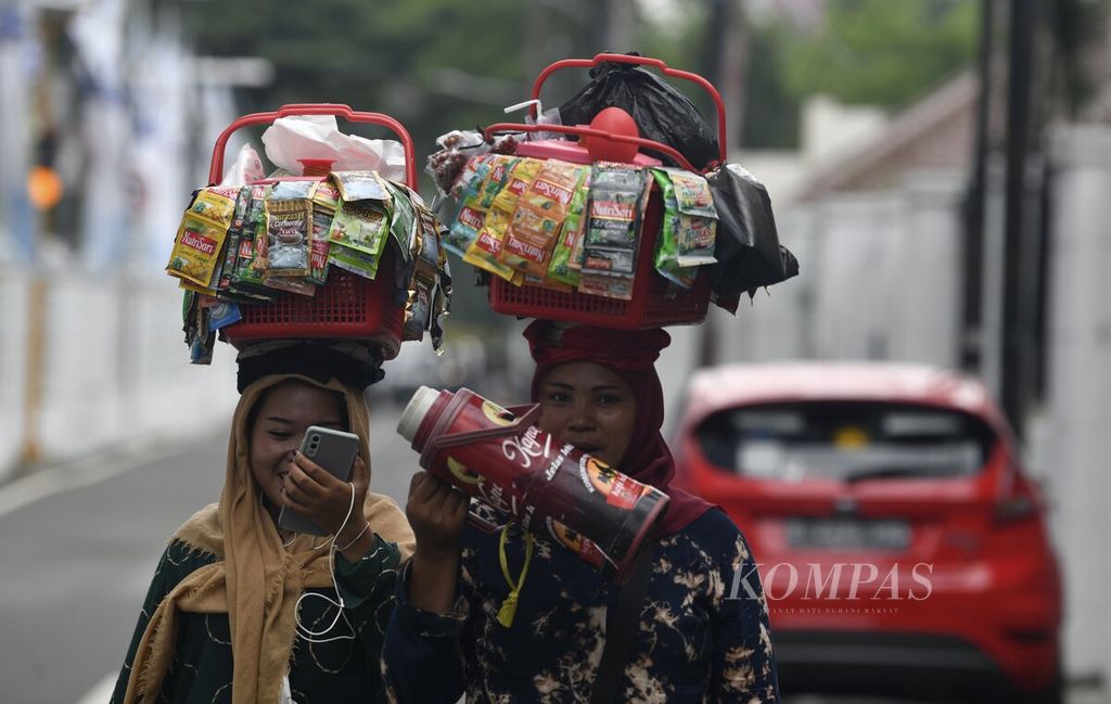 Penjual kopi instan dan minuman kemasan berkeliling di kawasan Gambir, Jakarta Pusat, Senin (15/11/2021). Aktivitas ekonomi informal yang lebih banyak berskala ultramikro dan mikro menjadi salah satu penopang ekonomi formal yang terpuruk saat pandemi. 