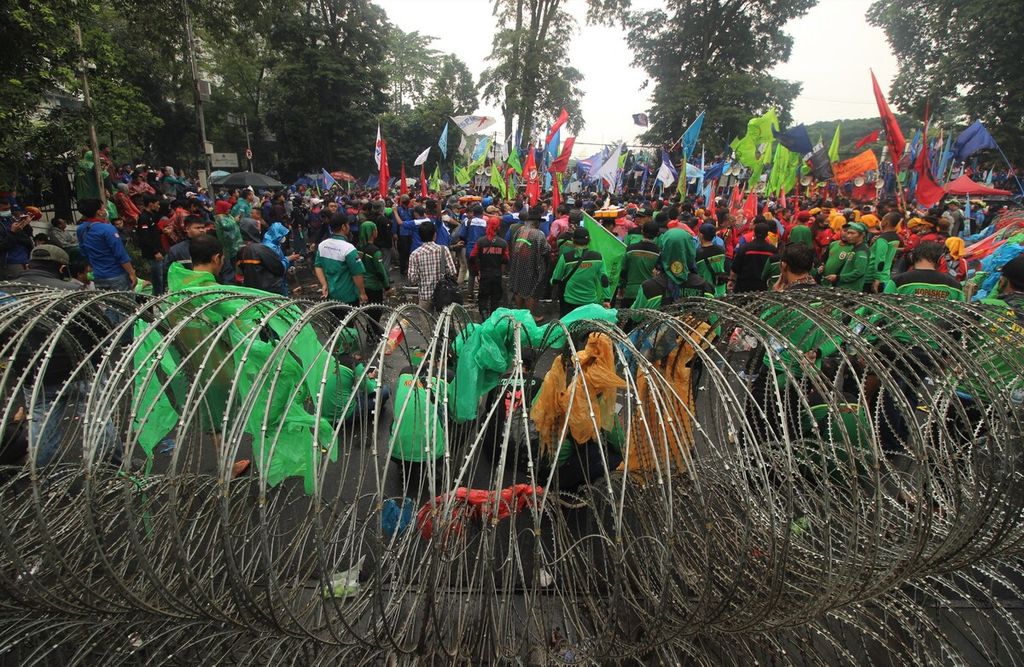 Ribuan pekerja berunjuk rasa di tengah guyuran hujan di depan Gedung Sate, Kota Bandung, Jawa Barat, Selasa (30/11/2021). 