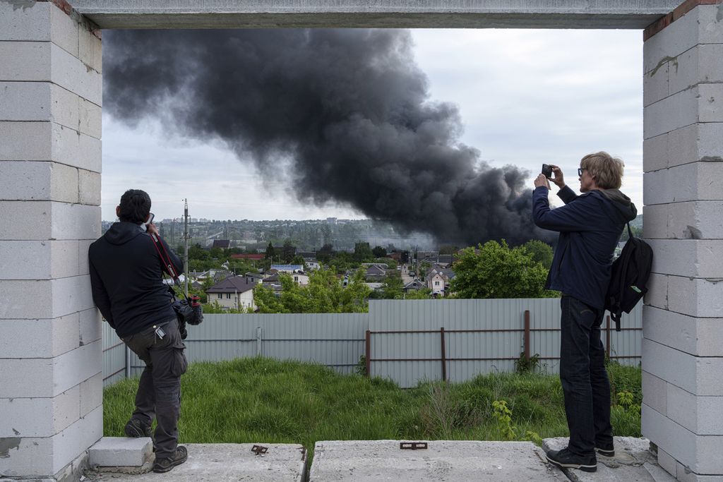 Foreign journalists photograph from an observation point as smoke rises after a Russian attack in Kharkiv, Ukraine, May 17, 2024. 