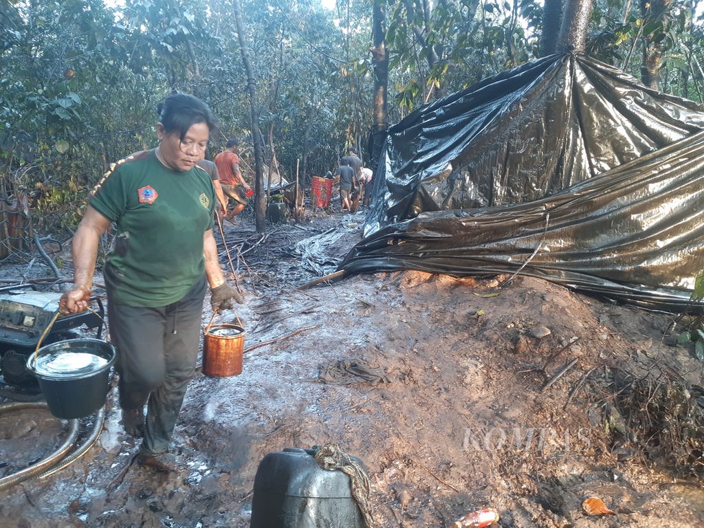 A woman carries crude oil with a bucket in an illegal mining area in Keluang Village, Keluang District, Musi Banyuasin Regency, South Sumatra, Friday (16/9/2022)..