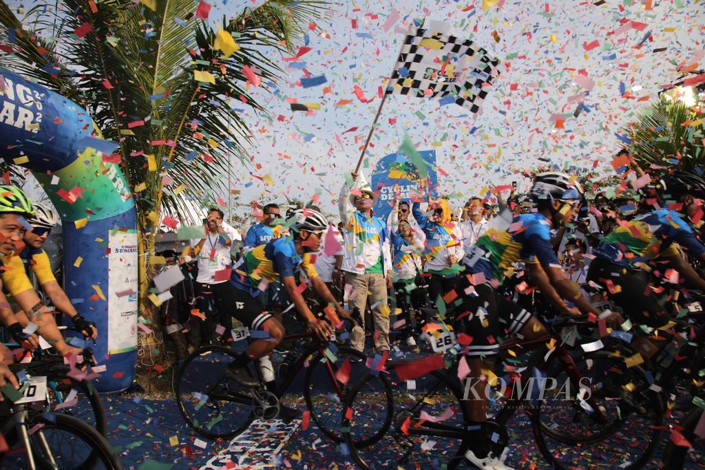 Gubernur Jawa Barat Ridwan Kamil mengangkat bendera start menandainya dimulainya balap sepeda Cycling de Jabar 2022 di Pantai Palangpang, kawasan Geopark Ciletuh, Kecamatan Ciemas, Kabupaten Sukabumi, Jawa Barat, Sabtu (27/8/2022).  