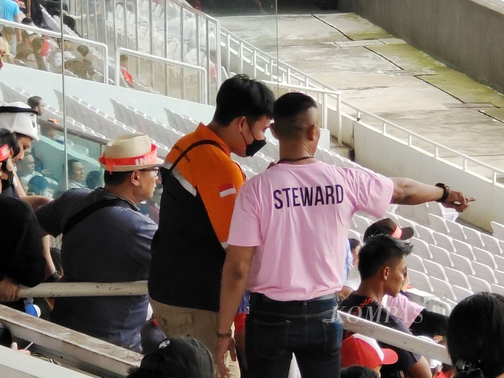 Petugas <i>steward</i> mengarahkan penonton saat laga Piala AFF 2022 antara Indonesia dan Kamboja di Stadion Gelora Bung Karno, Jakarta, Jumat (23/12/2022). Laga itu menjadi pertandingan pertama di Indonesia yang dihadiri penonton usai Tragedi Kanjuruhan. Tampak ada upaya untuk pembenahan penyelenggaraan pertandingan, tetapi masih jauh dari ideal. Bahkan, ada insiden antara suporter Ultras Garuda dan petugas keamanan tak lama usai babak kedua dimulai.