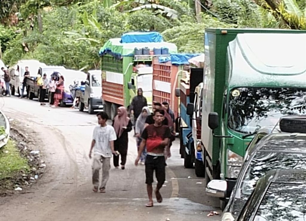 Antrean kendaraan dari arah Mamuju ke Majene dan sebaliknya mengular di lokasi longsor di Kecamatan Tubo Sendana, Majene, Sulawesi Barat, Jumat (28/10/2022). Material longsor yang menutup jalan membuat ruas di Trans Sulawesi ini lumpuh.