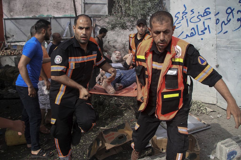 Anggota Pertahanan SIpil Palestina mengevakuasi seorang laki-laki yang terluka setelah roket menghantam kamp pengungsi Jebaliya, di wilayah utara Jalur Gaza, Minggu (7/8/2022). Serangan yang diduga dilakukan oleh Israel ini mengakibatkan enam orang warga Palestina tewas. (AP Photo/Ahmad Hasaballah)