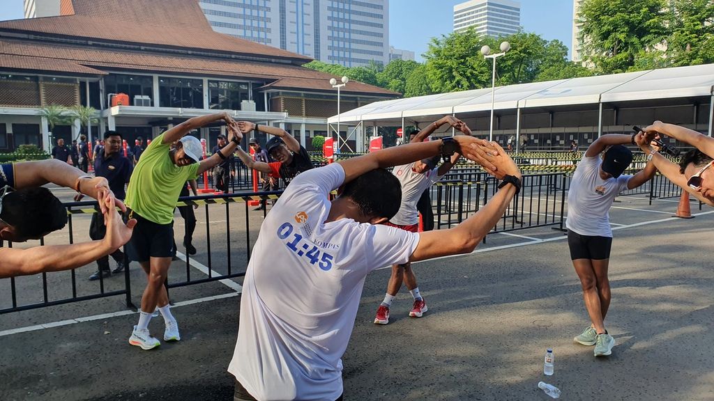 Para pelari dari berbagai komunitas melakukan pemanasan sebelum mengikuti acara Run The Ground with The Pacer sejauh 18 kilometer mengitari Jalan Sudirman-Thamrin, Minggu (18/6/2023).