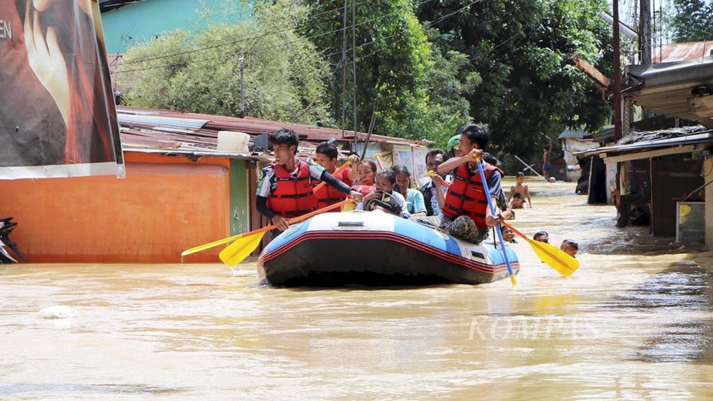 Petugas mengevakuasi warga yang terjebak di rumah yang diterjang banjir di Jalan Dipanegara, Kecamatan Medan Baru, Medan, Sumatera Utara, Minggu (16/9/2018). 