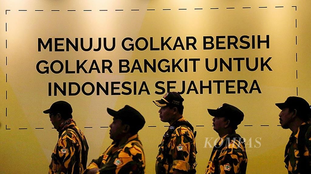 Kader Partai Golkar melintas di depan tulisan yang terpampang di lokasi pelaksanaan Musyawarah Nasional Luar Biasa Partai Golkar di Jakarta, Selasa (19/12/2017). 